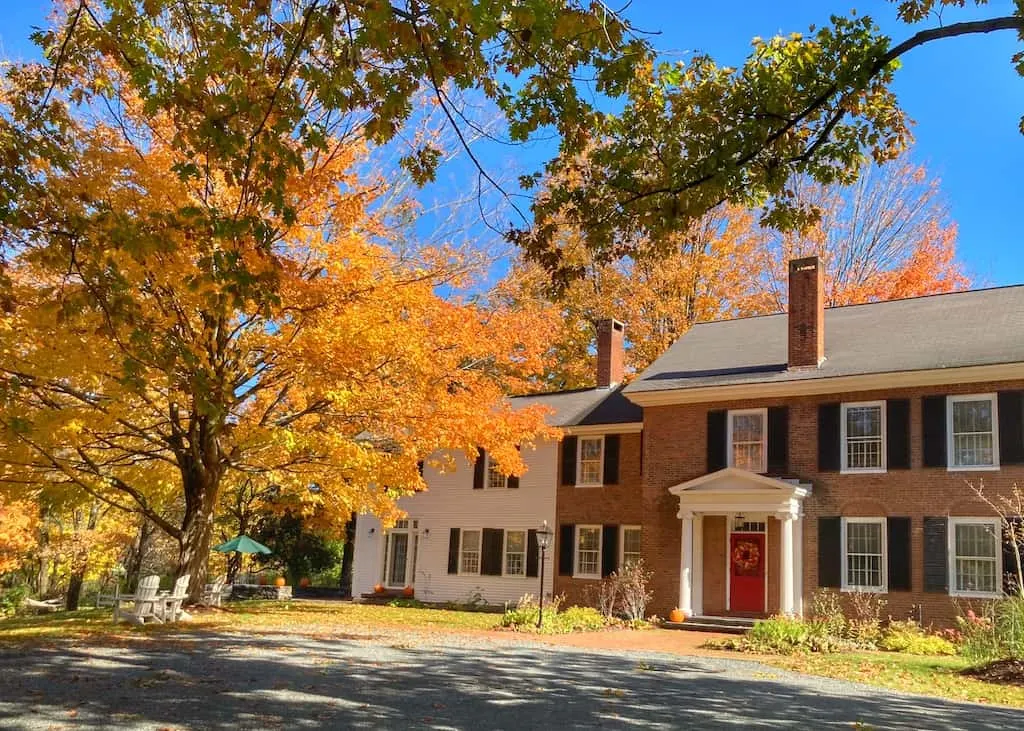 A historic home in downtown Woodstock, Vermont surrounded by fall foliage.