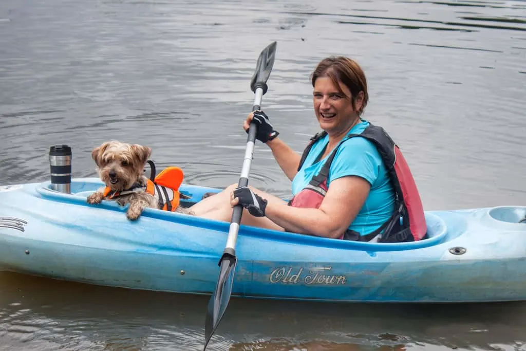 A woman and her small dog launch a kayak onto the Connecticut River.