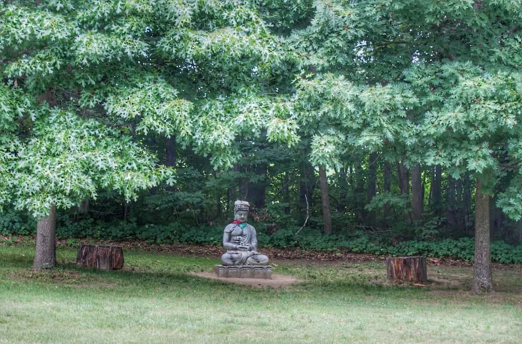 Buddha under trees in the Path of Life Garden in Windsor, VT.