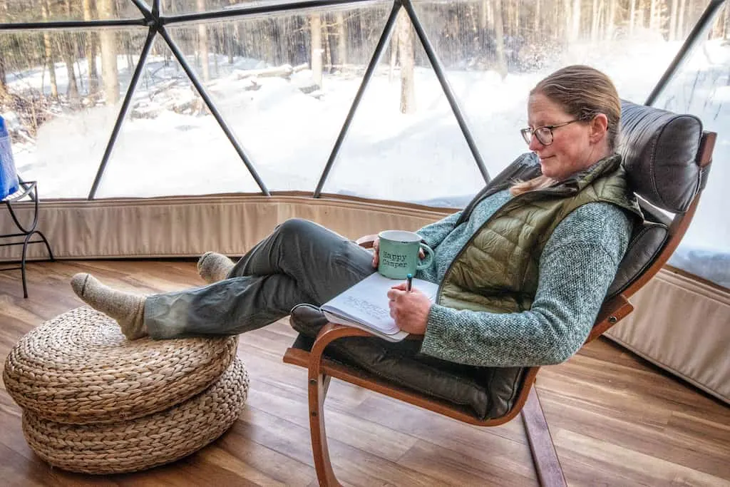 I'm relaxing in a chair writing in my notebook near the window of the geodesic dome.