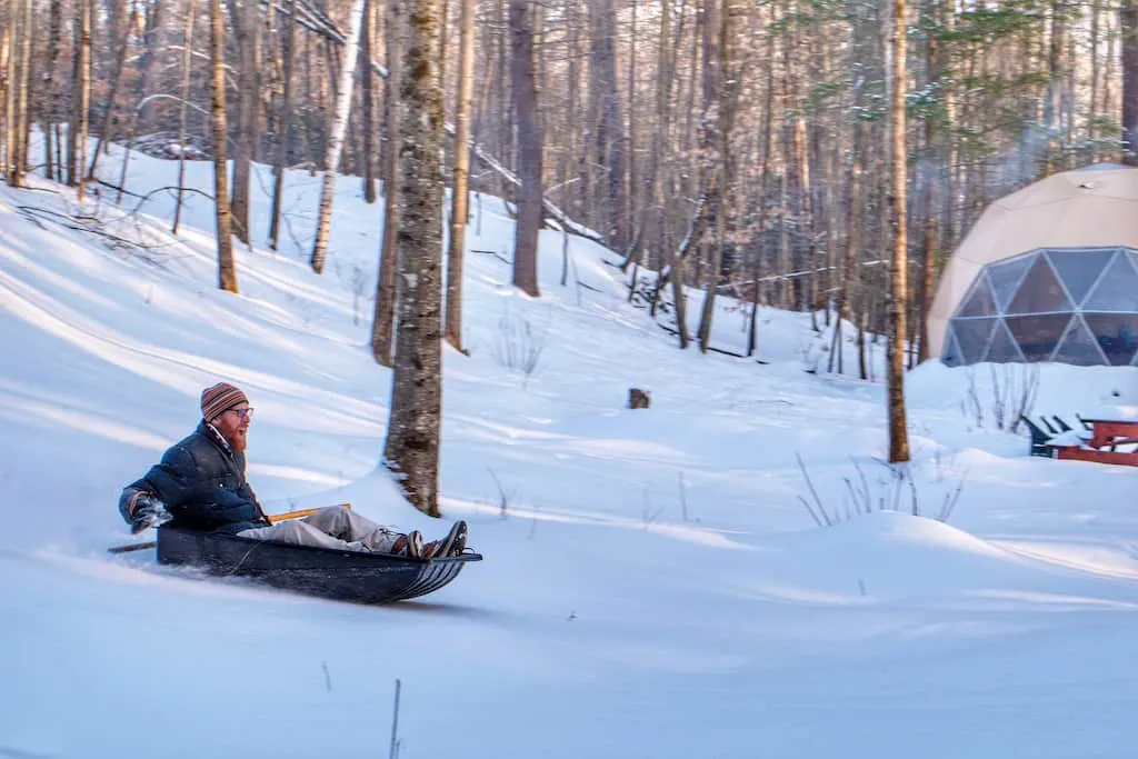 Eric sleds down a wooded hill in Vermont.