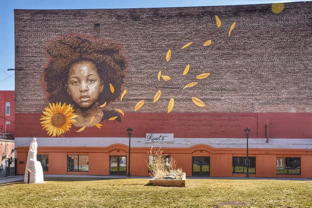 A mural of a girl next to a sunflower called "We Who Believe in Freedom Cannot Rest Until it Comes" in Rutland, Vermont.