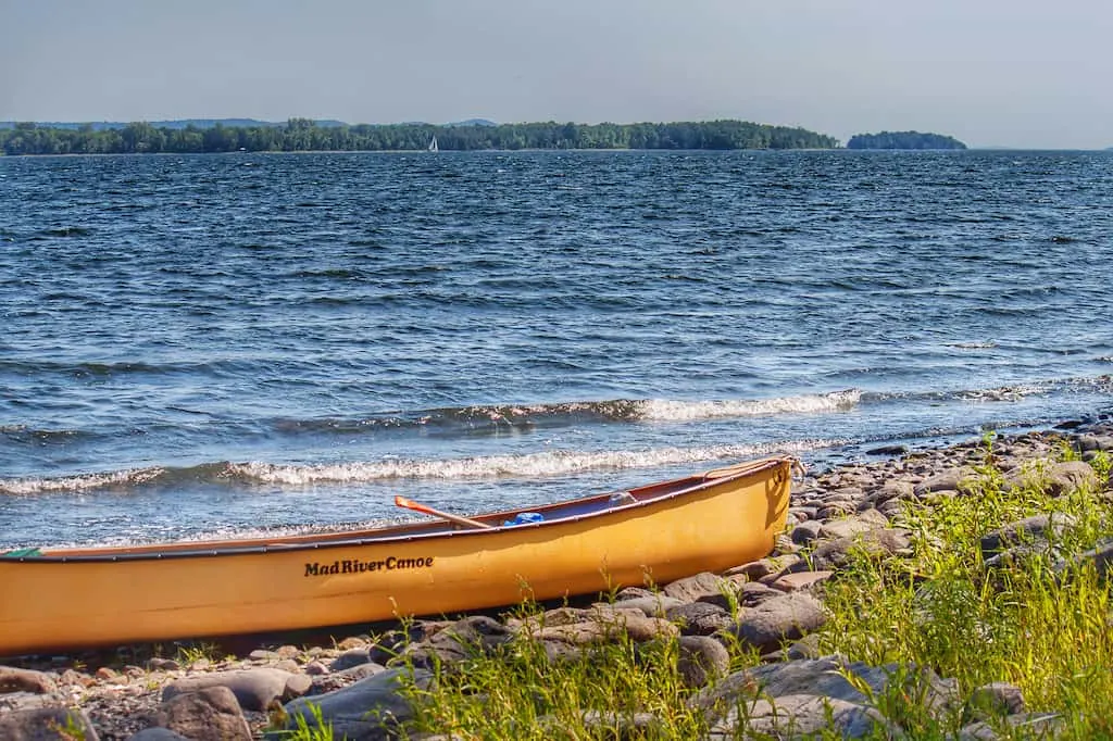 A yellow Mad River canoe beached on an island in Lake Champlain, Vermont.