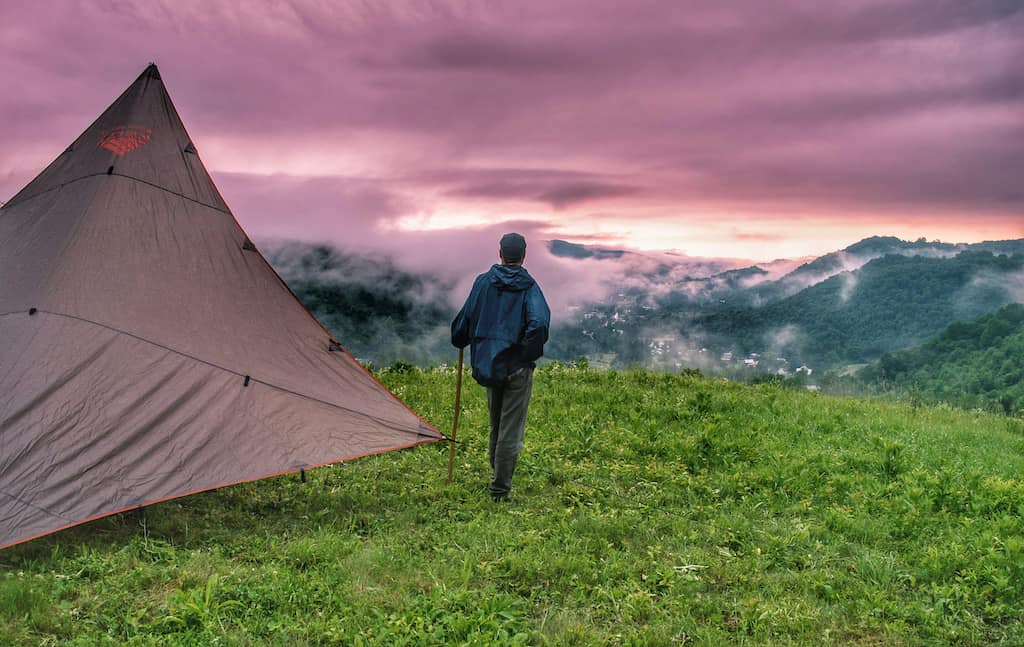 A man stands looking at the mountains while camping on a Vermont farm in Chelsea, Vermont.