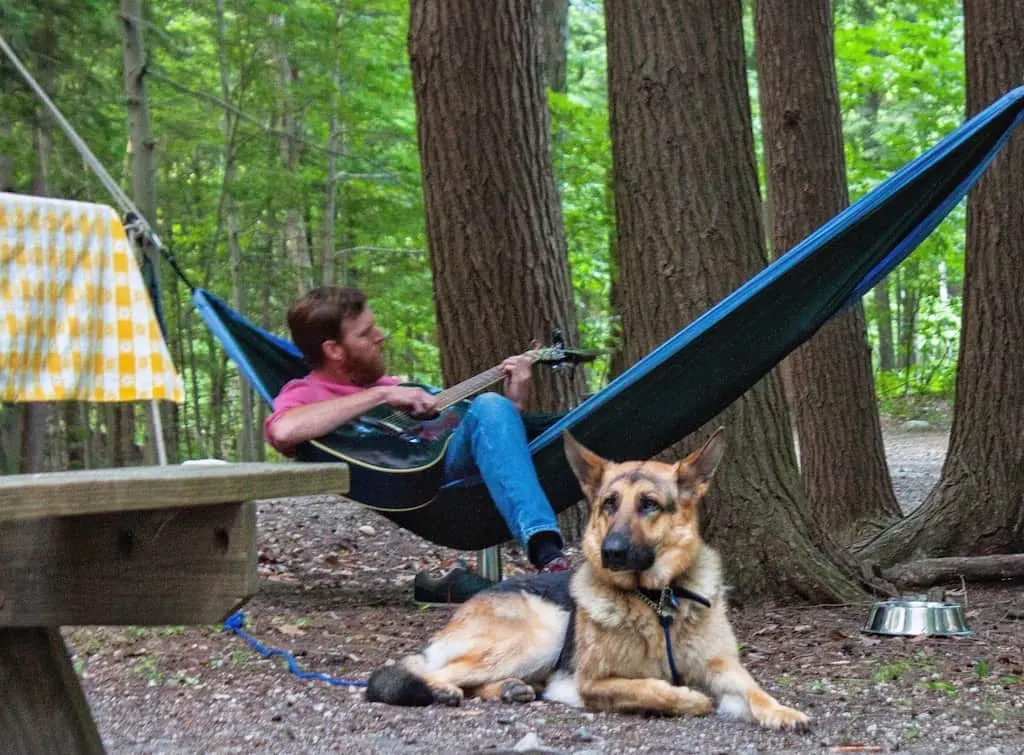 Eric plays the guitar in our camping hammock while Ogden the German Shepherd lies nearby.