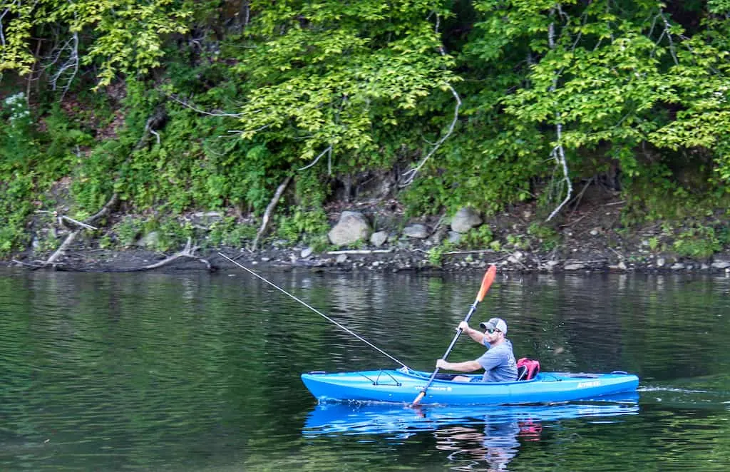 A man paddles a kayak in Waterbury Reservoir while fishing for trout in Vermont.