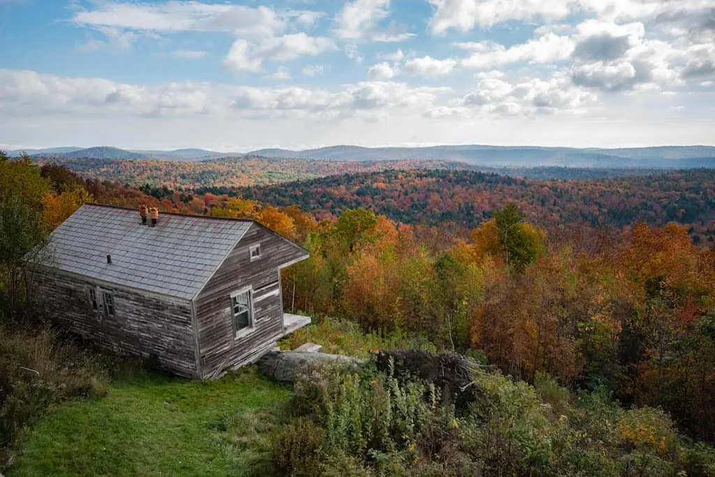 A view of an old cabin perched on the side of a mountain in Wilmington, Vermont during fall foliage season.
