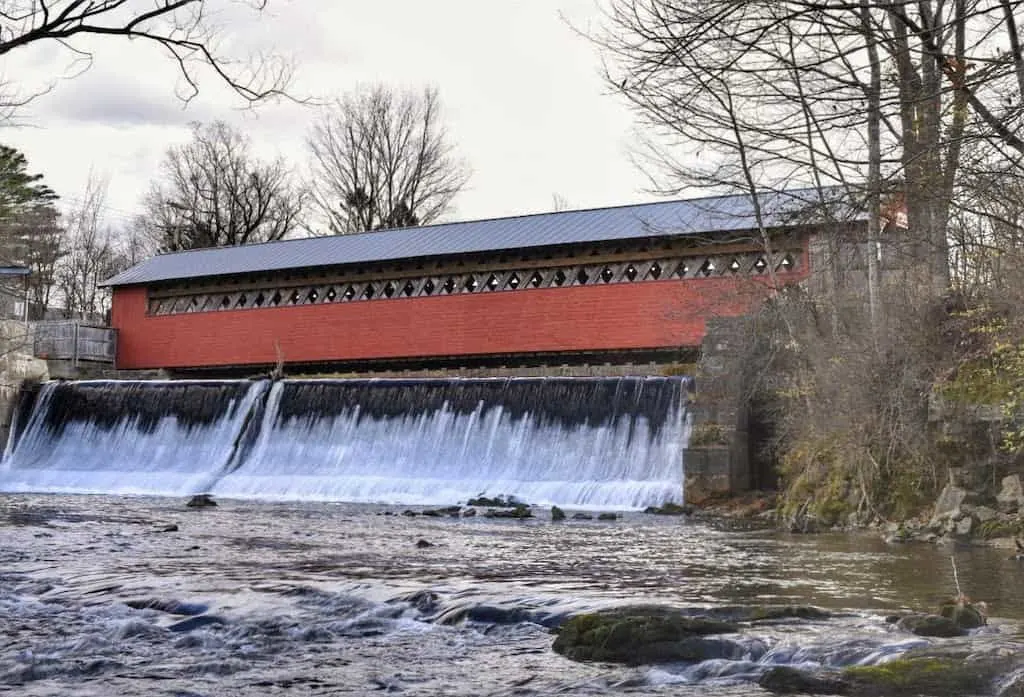 A dam and waterfall running underneath the Paper Mill Village Bridge in Bennington, VT.