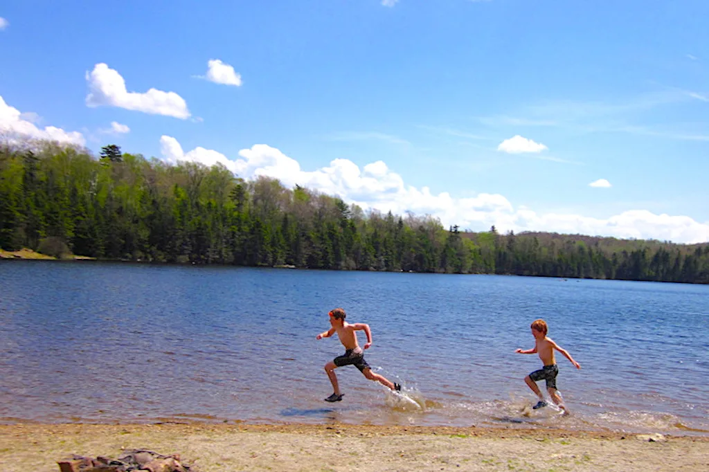 Two kids running through the water in a lake in Southern Vermont.