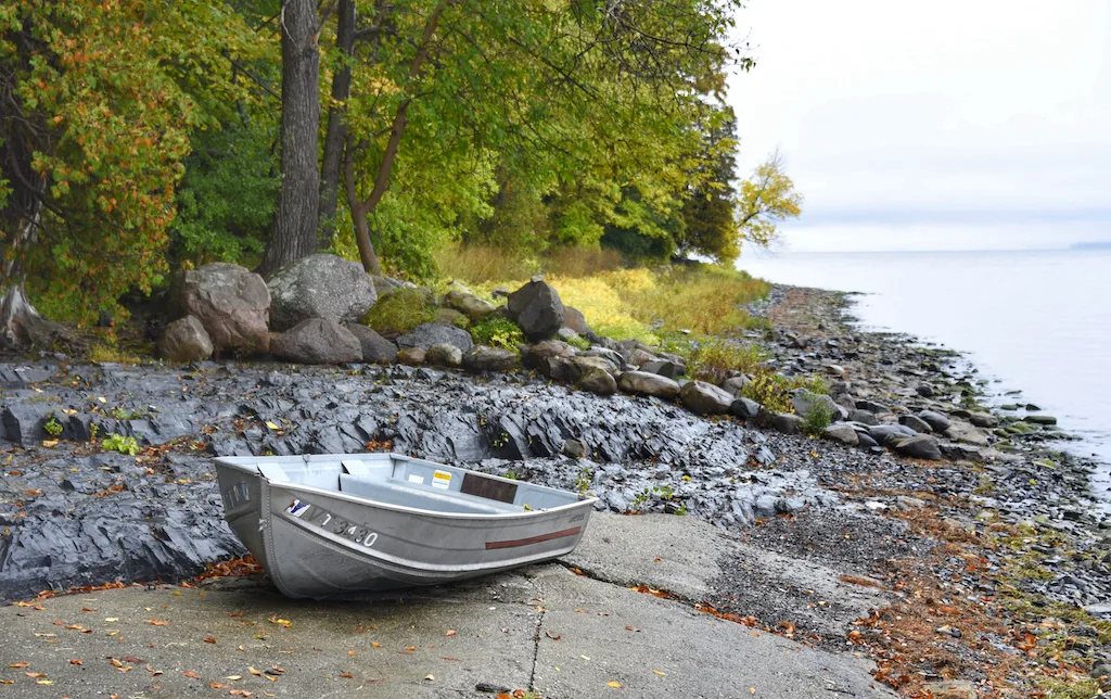 A rowboat on the shore of Lake Champlain in the fall.