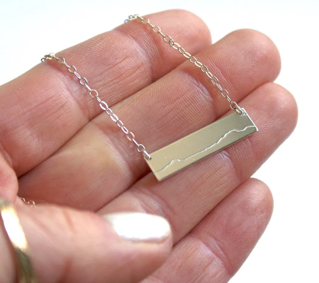 A small necklace with the outline of Mount Mansfield stamped on it. 