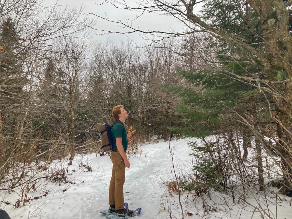 A man in snowshoes hikes the trail up Haystack Mountain in Vermont during the winter.