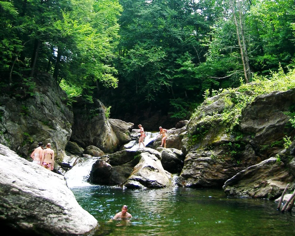 A group of people enjoy the Three Holes swimming area in Vermont.