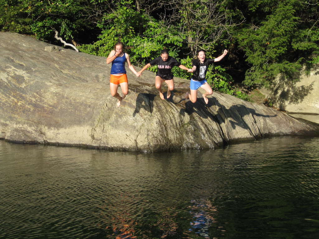 A group of young people cliff jumping in Vermont at a local swimming hole.