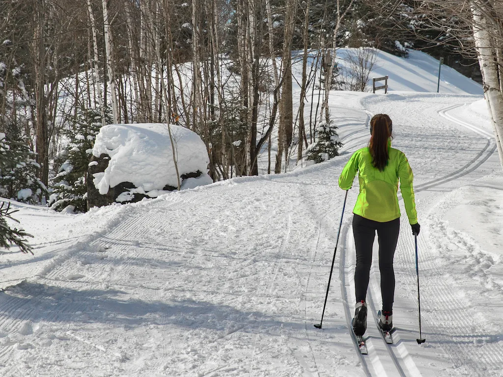 A woman cross-country skis through the woods in Woodstock, Vermont in the winter.
