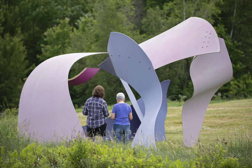 Two people enjoy outdoor sculpture parks in Vermont. 
