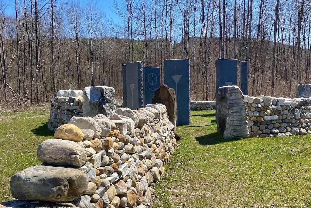 A sculpture at the Carving Studio in West Rutland, featuring standing stones and several stone walls.
