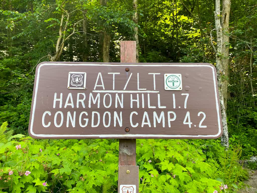 The trail sign at the trail head for Harmon Hill. Reads: "AT/LT, Harmon Hill 1.7 mi, Congdon Camp 4.2 mi"
