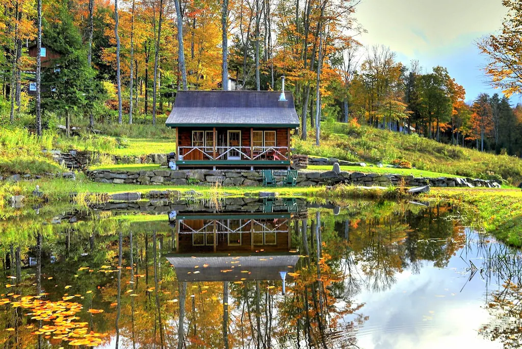 A cabin for rent in Vermont on a trout pond surrounded by fall foliage. 