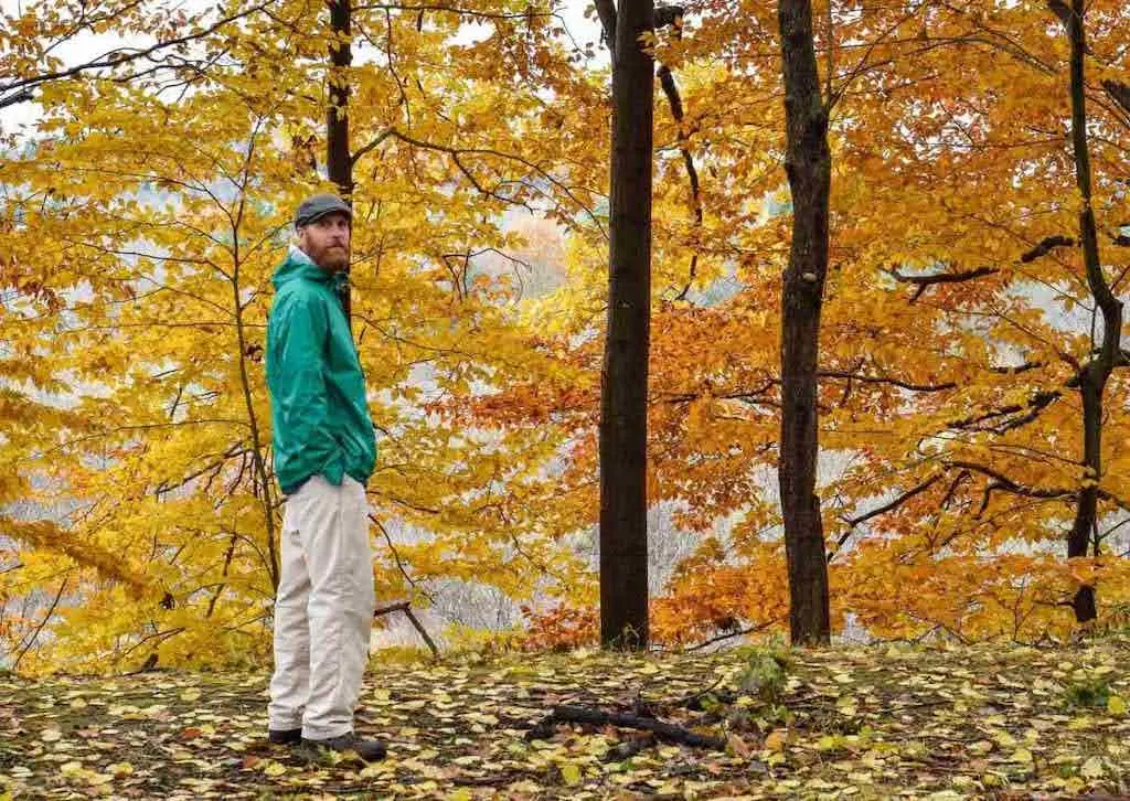 Eric wearing a blue rain coat in the woods.