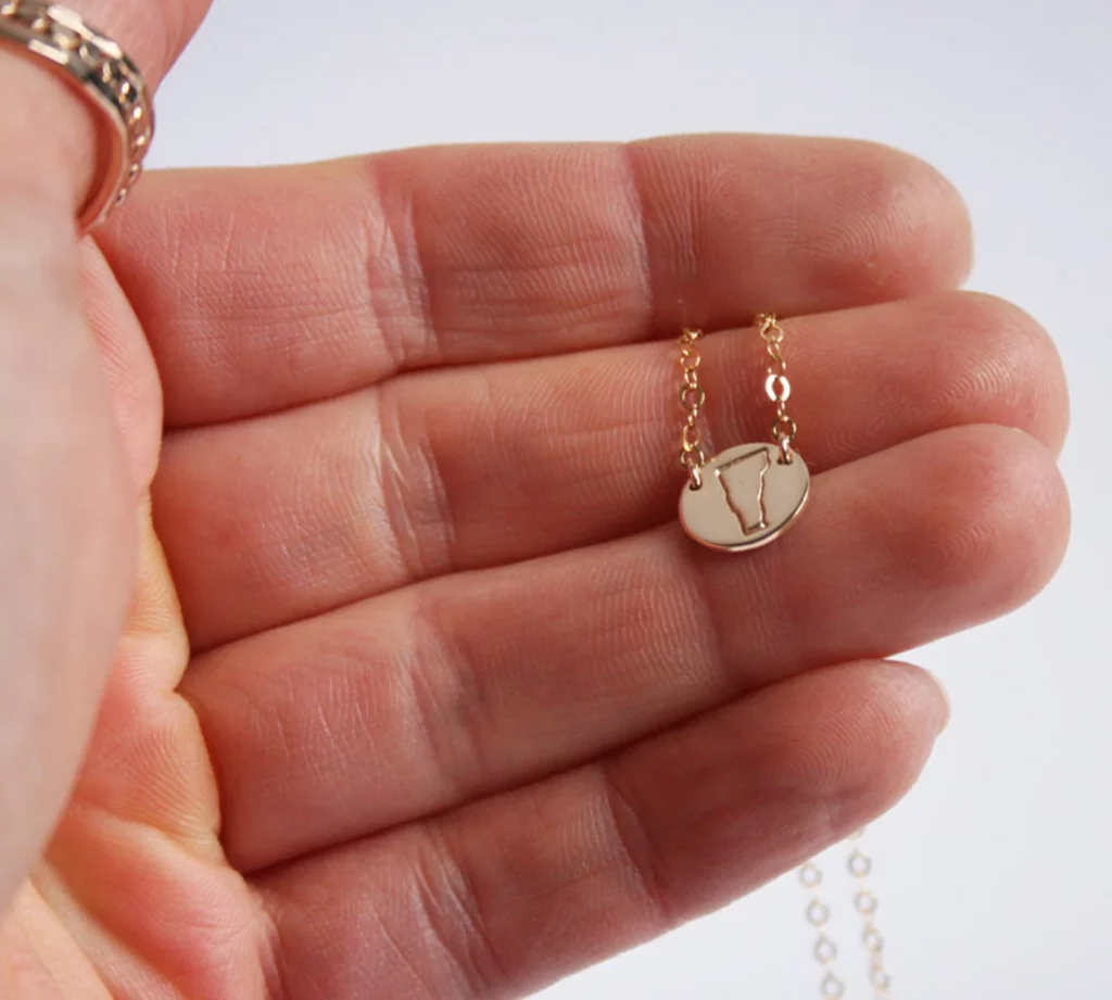 a tiny gold necklace in the shape of Vermont.