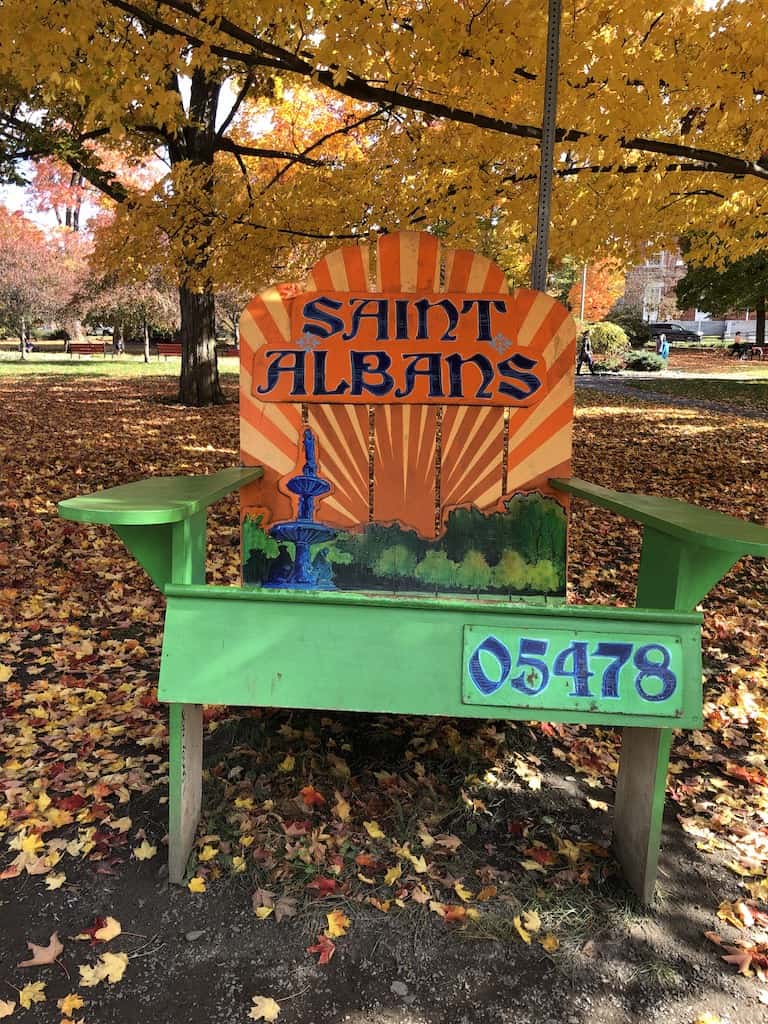 Saint Albans welcome sign on a green Adirondack Chair. 