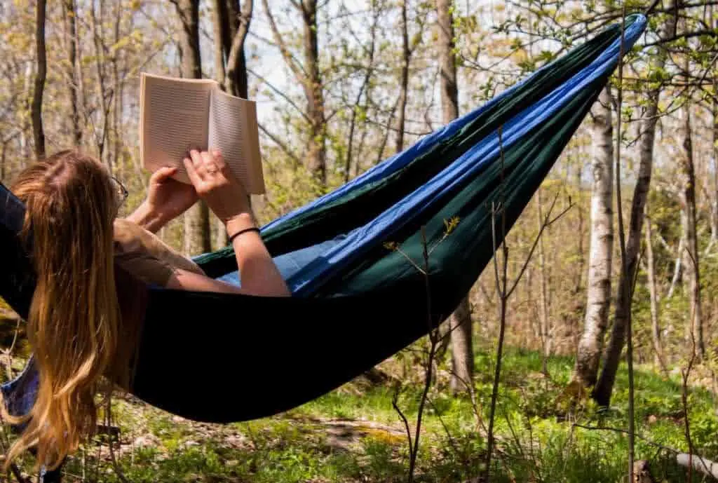 Tara lies in a hammock reading a book about Vermont.