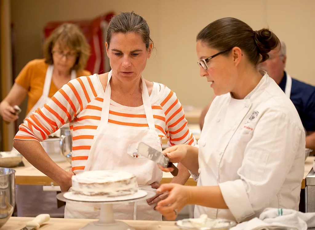 Two bakers wort to decorate at cake at King Arthur Baking in Vermont. 