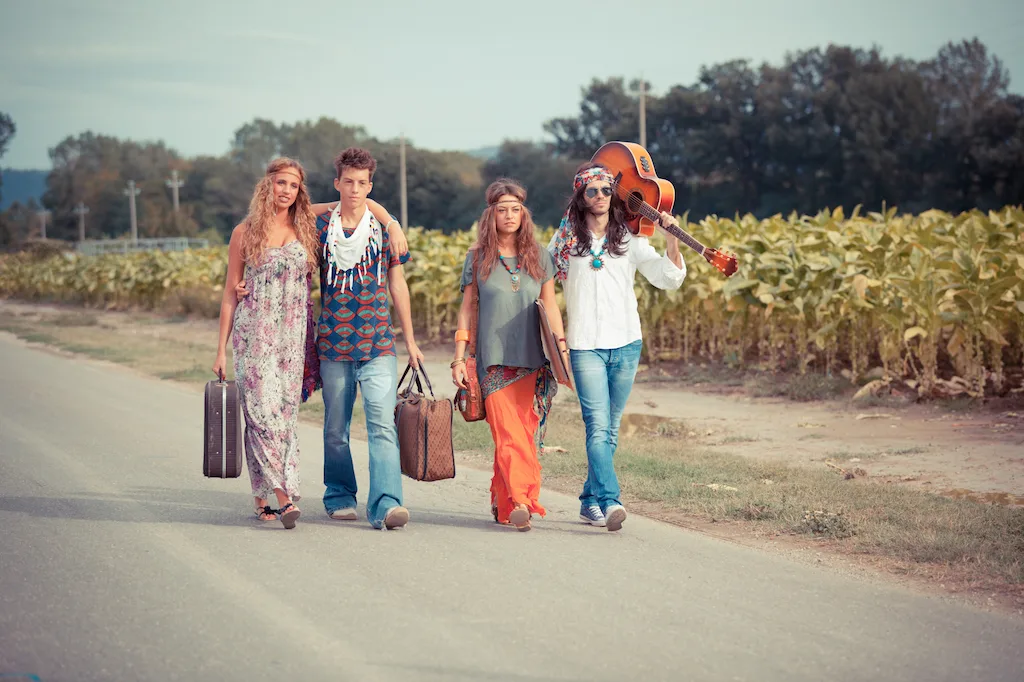 Hippies walking down the street in front of a corn field. 