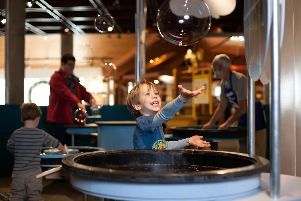 A child reaches toward a giant bubble inside Montshire Museum in Norwich, Vermont.