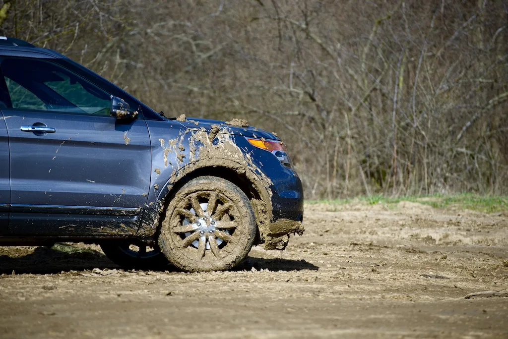A blue car covered with mud in Vermont.