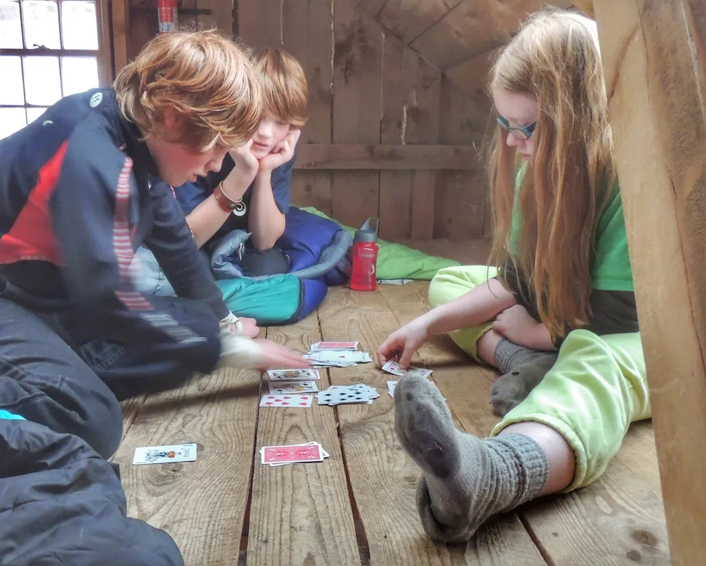 Three kids playing cards in a cabin in Vermont.
