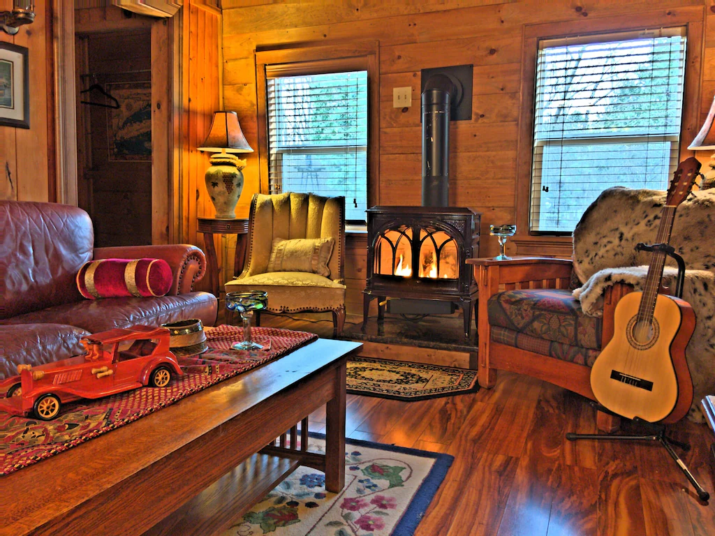 The interior of a cozy living room with a woodstove and a guitar. Available for rent on VRBO.