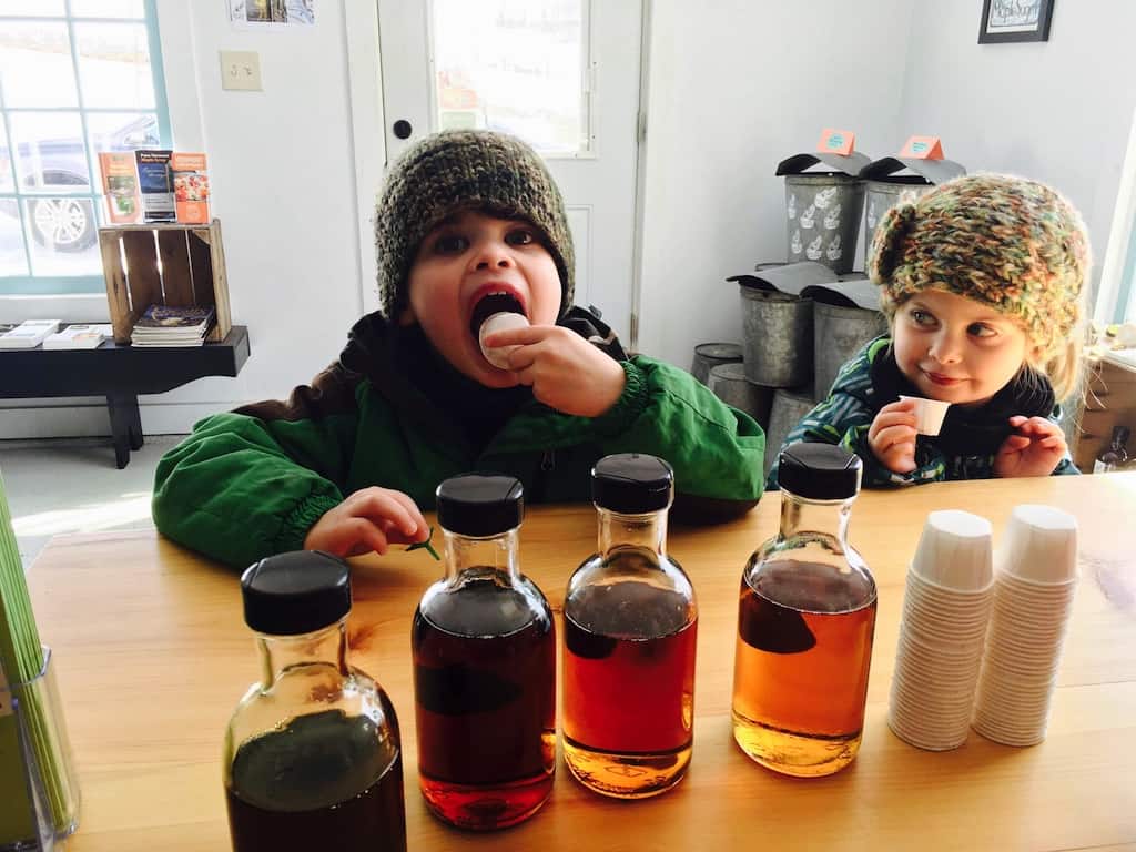 Two kids tasting maple syrup during Vermont Maple Open House Weekend.
