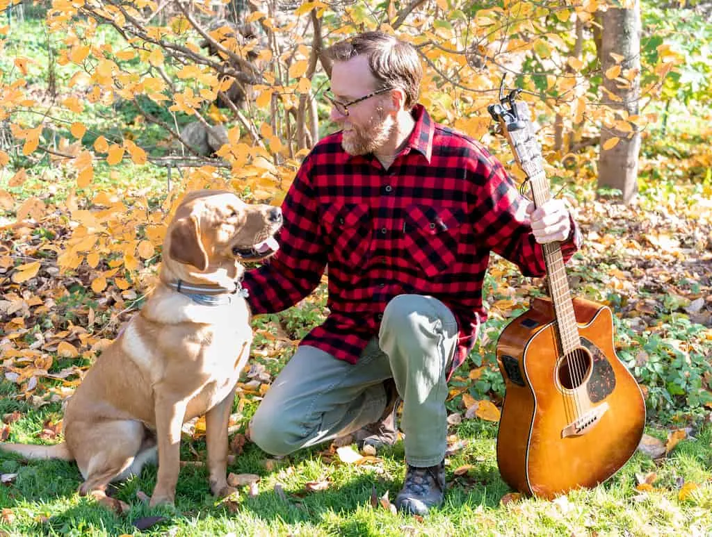 Eric wearing a Vermont Flannel and posing with yellow lab, Brutus.