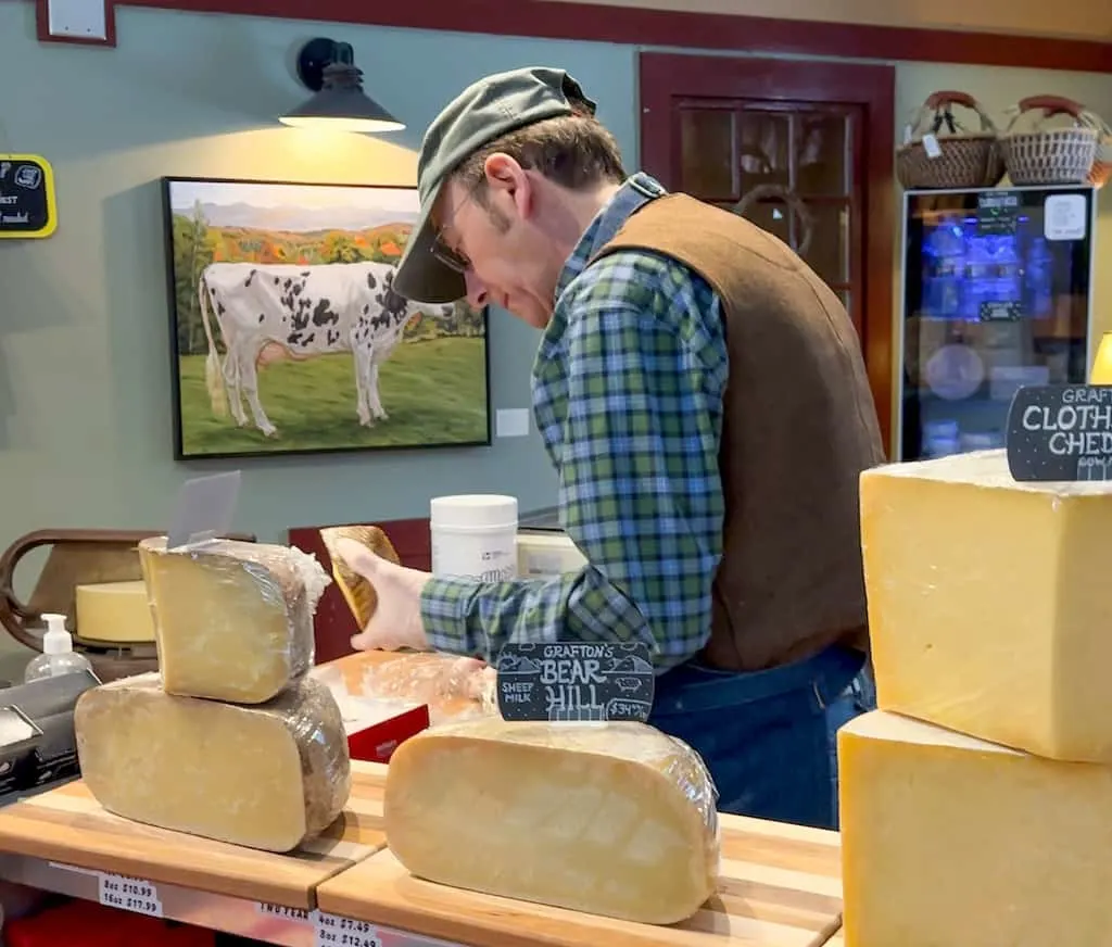A man cutting up cheese to offer as samples at Grafton Village Cheese. 