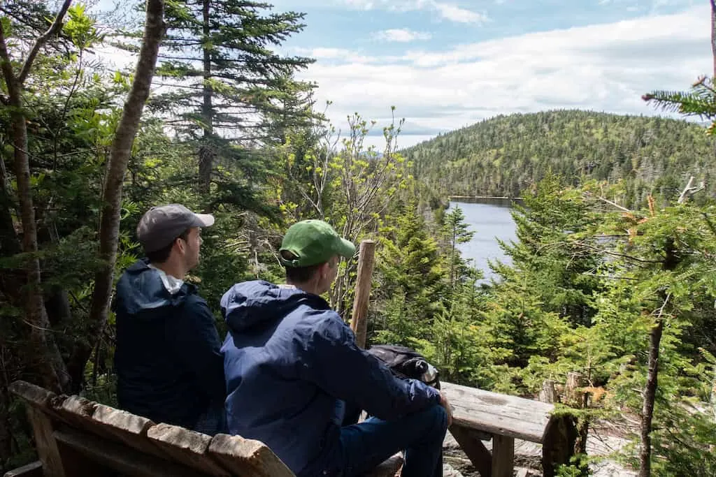 Two men sit on a bench and look out at the view over Sterling Pond. 