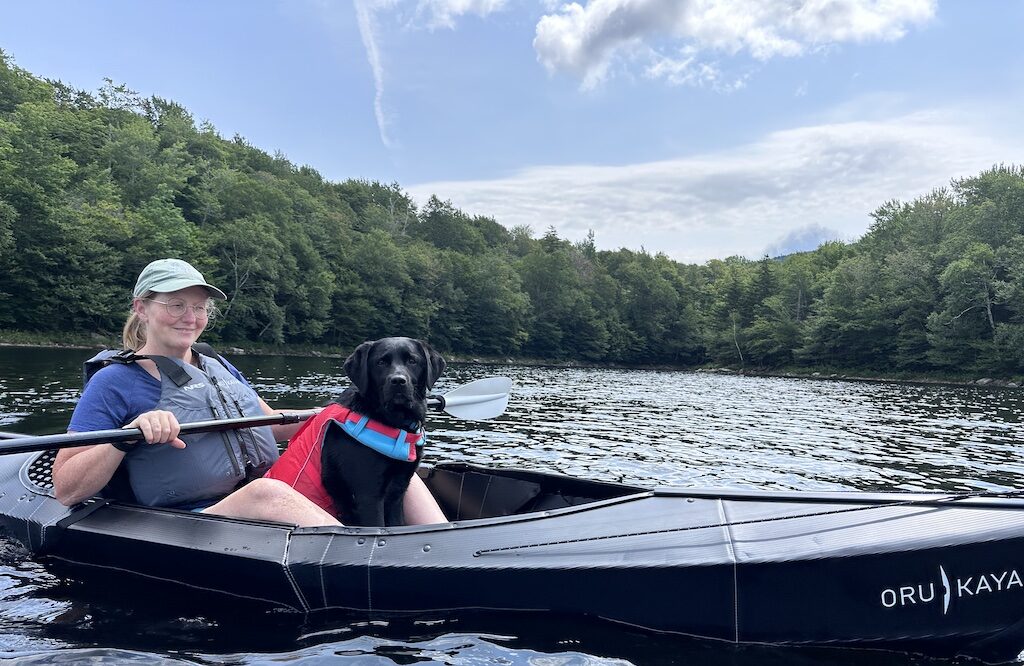 A woman kayaking with a dog in Vermont.