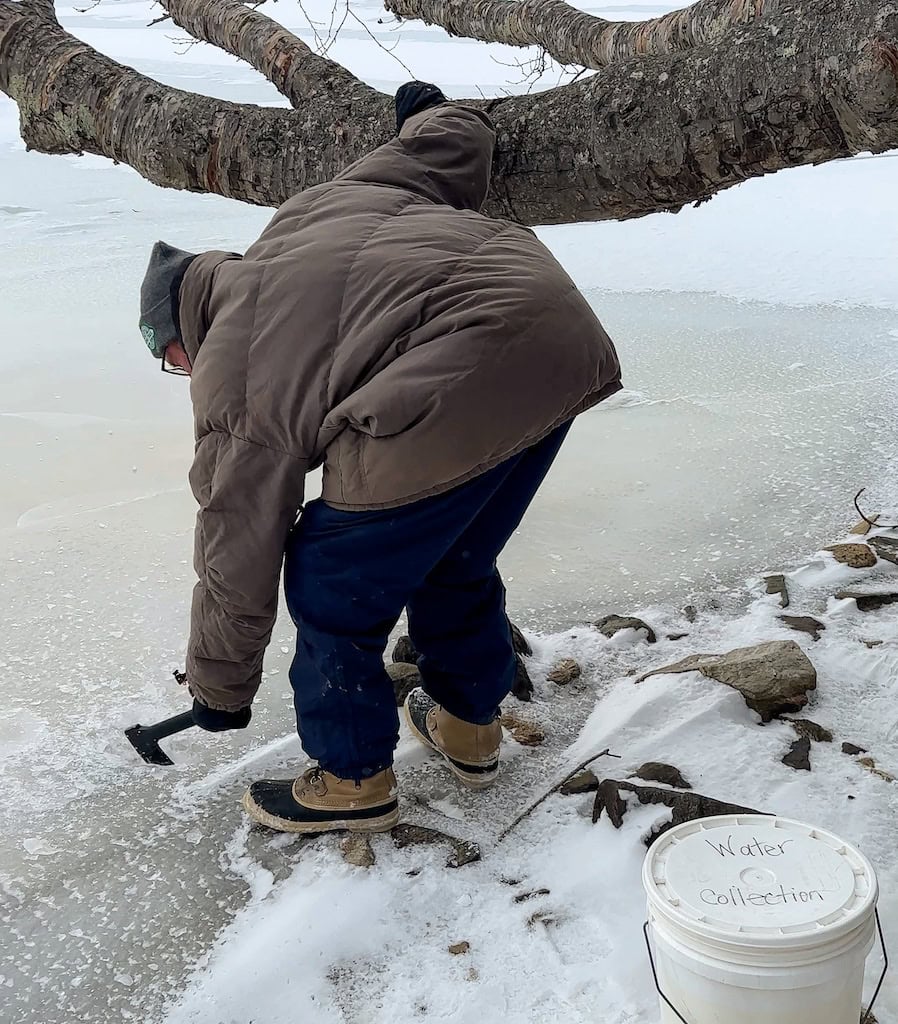 Eric using a hatchet to break ice on Grout Pond. 