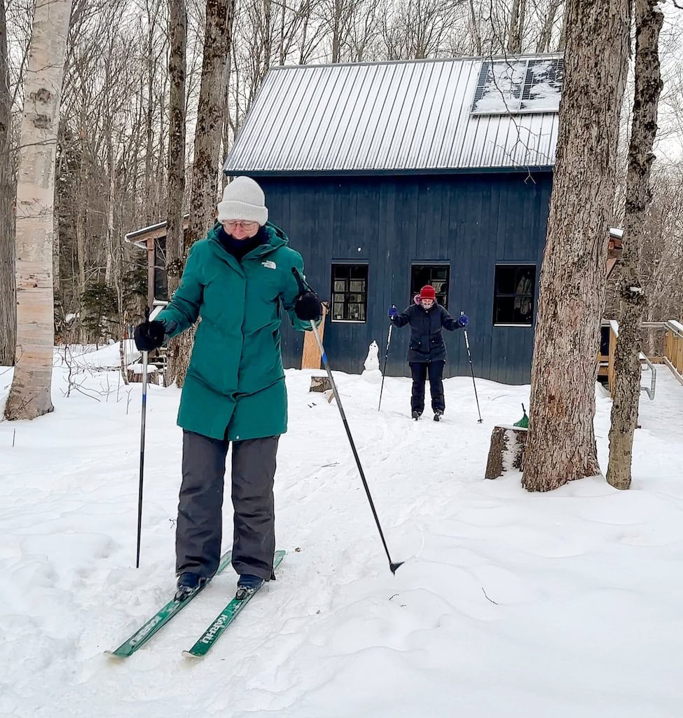 Beth and Abbey on cross-country skis in front of the hut. 